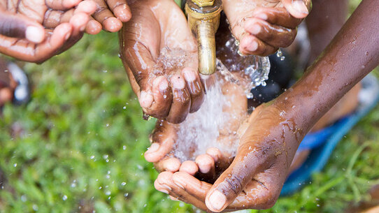 Ugandan children washing their hands at an outdoor water tap